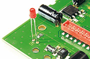 Die Leuchtdiode D 1 benötigt einen Leiterplattenabstand von 19 mm, gemessen von der LED-Spitze bis zur Platinenoberfl äche. Beim Einlöten ist unbedingt die korrekte Polarität zu beachten. Am Bauteil ist die Anode durch einen längeren Anschluss und im Bestückungsdruck ist die Anodenseite mit einem „+“ gekennzeichnet. Die Leuchtdiode D 1 benötigt einen Leiterplattenabstand von 19 mm, gemessen von der LED-Spitze bis zur Platinenoberfl äche. Beim Einlöten ist unbedingt die korrekte Polarität zu beachten. Am Bauteil ist die Anode durch einen längeren Anschluss und im Bestückungsdruck ist die Anodenseite mit einem „+“ gekennzeichnet.